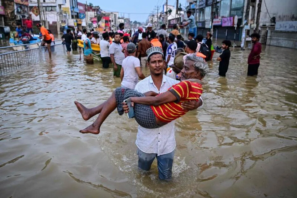 A youth carries an elderly man as they wade through a flooded street after heavy rainfall in Wellampitiya on the outskirts of Colombo.