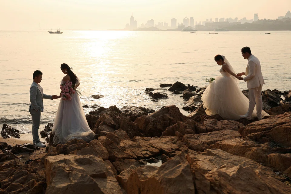 Couples take part in wedding photoshoots by the sea in Qingdao, Shandong province, China, April 21, 2024. More than 6.1 million couples registered for marriage last year, down from 7.68 million a year earlier, figures from the Ministry of Civil Affairs showed. 