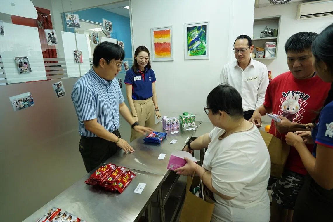 Mee Fong (foreground, in white), a person with intellectual disabilities, learns the basics of purchasing goods with money through classroom exercises.