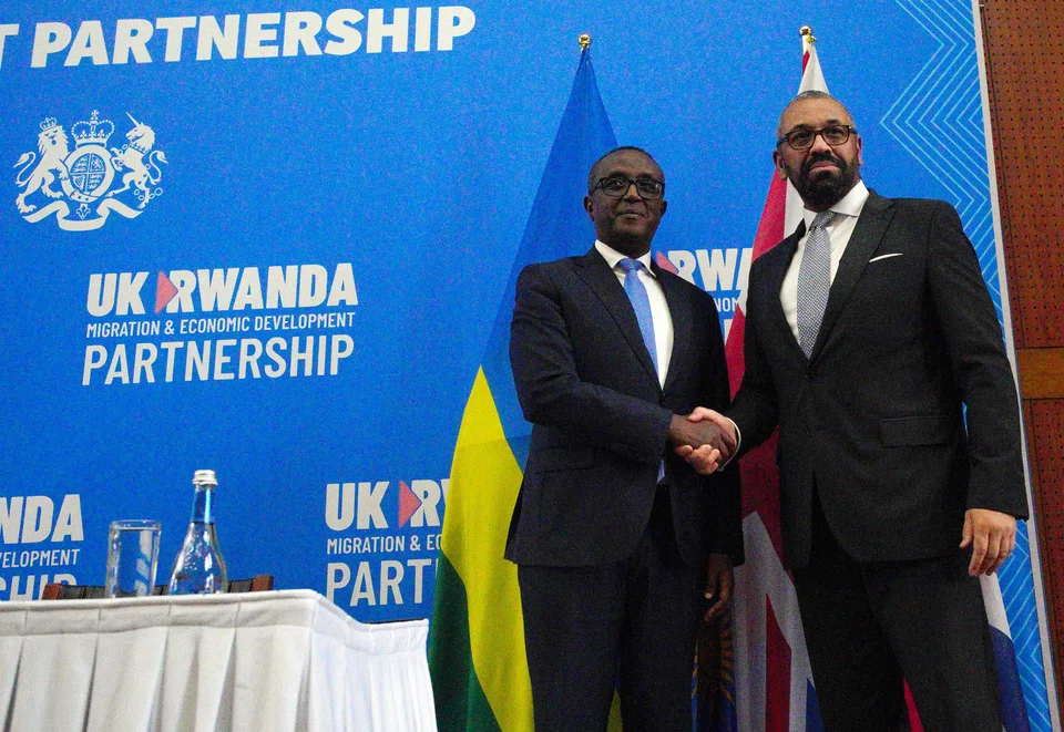Britain's Home Secretary James Cleverly (R) and Rwanda's Foreign Minister Vincent Biruta shake hands after signing a new treaty to revive a controversial proposal by London to transfer migrants to the east African country. 