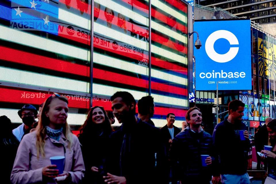 FILE — Coinbase employees gather in Times Square to see the launch of the company’s initial public offering displayed on the Nasdaq tower, April 14, 2021. Crypto companies are laying off staff, freezing withdrawals and trying to stem losses, raising questions about the health of the ecosystem. (Gabby Jones/The New York Times)