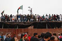 People waves Bangladeshi flags on top of the Ganabhaban, the Prime Minister's residence, as they celebrate the resignation of PM Sheikh Hasina in Dhaka, Bangladesh, Aug 5, 2024. 