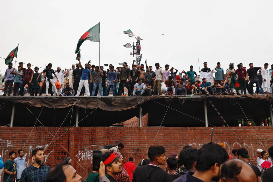 People waves Bangladeshi flags on top of the Ganabhaban, the Prime Minister's residence, as they celebrate the resignation of PM Sheikh Hasina in Dhaka, Bangladesh, Aug 5, 2024. 