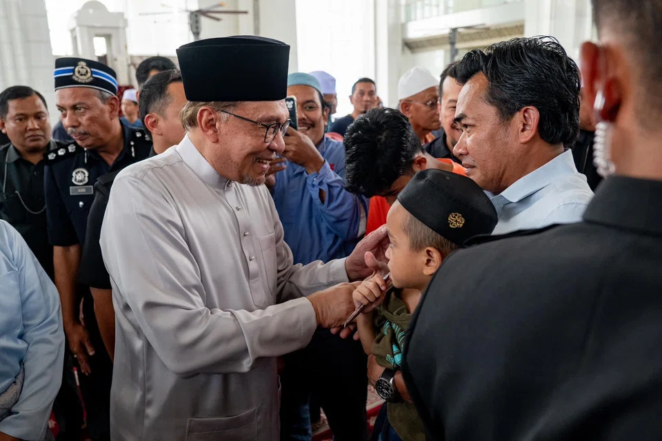 Malaysian PM Anwar Ibrahim greeting congregants at a mosque in Putrajaya after Friday prayers on Oct 18, before he delivered the Budget 2025 statement in parliament.