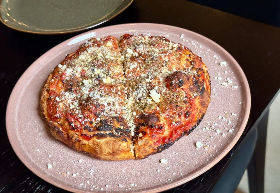 Pizza in teglia is a mini pizza topped with tomato sauce and grated cheese.