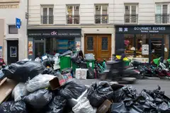 Overflowing garbage bins and bags of trash left on the street in the 8th arrondissement of Paris, France, on Feb 15, 2023. Striking garbage collectors have left trash to pile up in the streets for the last week in protest against President Emmanuel Macron's plan to raise the retirement age.