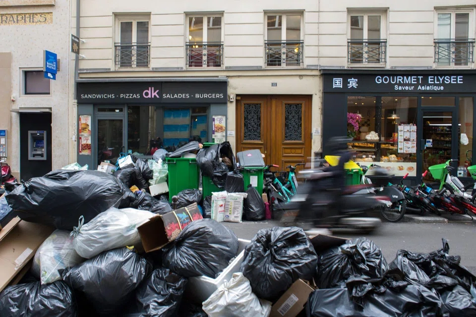 Overflowing garbage bins and bags of trash left on the street in the 8th arrondissement of Paris, France, on Feb 15, 2023. Striking garbage collectors have left trash to pile up in the streets for the last week in protest against President Emmanuel Macron's plan to raise the retirement age.