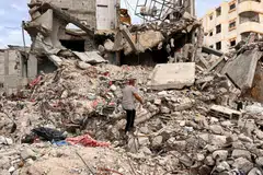 Palestinian Moein Abu Odeh searches for clothes through the rubble of a house destroyed in the Israeli military offensive, in Khan Younis in the southern Gaza Strip.