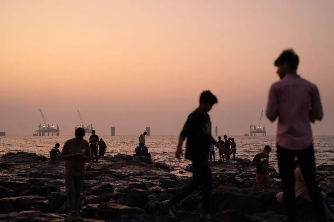 People on the rocks along the Bandstand Promenade in the suburb of Bandra in Mumbai, India, on Friday, Jan. 3, 2025. India’s new central bank governor said the economy will probably rebound next year on the back of strong consumer and business confidence, his first public comments about the growth outlook since he took office earlier this month. Photographer: Abeer Khan/Bloomberg