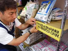A supermarket worker in Tokyo putting up a sign informing customers purchasing rice to buy only one bag per person. 
