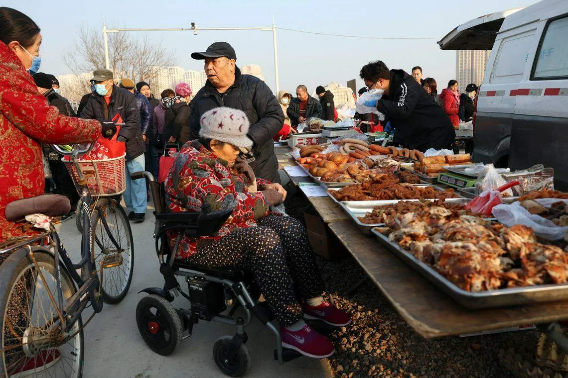 Elderly people chat next to a food stall at an outdoor market in Beijing, China January 12, 2024. REUTERS/Florence Lo