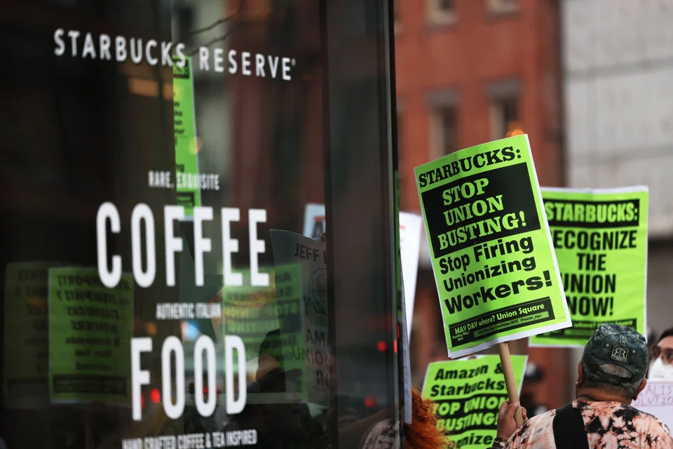 People hold signs while protesting in front of Starbucks on Apr 14, 2022 in New York City. Activists gathered to protest Starbucks' CEO Howard Schultz anti-unionisation efforts and demand the reinstatement of workers fired for trying to unionise.