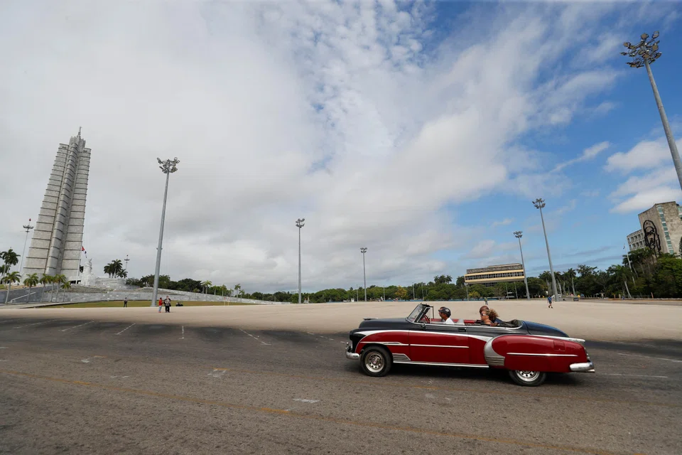 Tourists ride in a vintage car at the Revolution Square in Havana, Cuba.