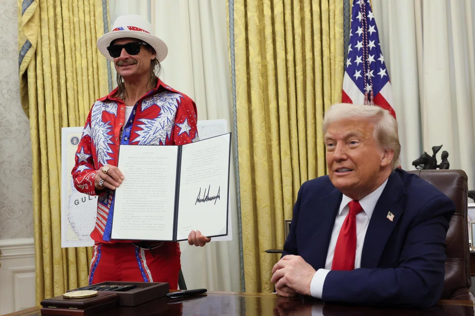Kid Rock holds an executive order signed by US President Donald Trump related to the US live entertainment ticketing industry in the Oval Office at the White House in Washington.
