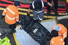A body is transferred into a vehicle in the aftermath of a major fire that swept through apartment blocks at the Wang Fuk Court residential estate in Hong Kong.