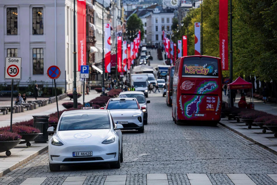 Oslo Taxi's Tesla model Y (L) and the NIO ET5 electric vehicle from Nio Inc, a Chinese multinational electric car manufacturer, drive through the Norwegian capital Oslo, on September 27, 2024. Despite being a major oil and gas producer, Norway has adopted the most ambitious objective in the world. The plan is that only "zero emission" private cars will be sold from 2025 and onwards. (Photo by Jonathan NACKSTRAND / AFP)