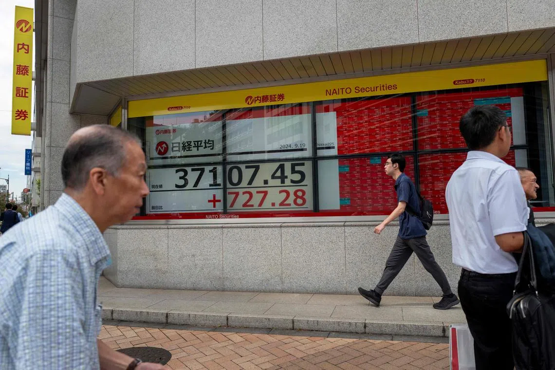 Pedestrians walk past an electronic quotation board displaying the Nikkei index on the Tokyo Stock Exchange in Tokyo on September 19, 2024. (Photo by Kazuhiro NOGI / AFP)