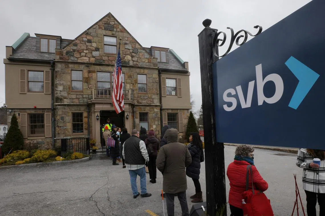 Customers wait in line outside a branch of the Silicon Valley Bank in Wellesley, Massachusetts, US, March 13, 2023.     