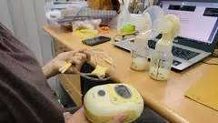 A breastfeeding mother expressing milk at her desk at work.