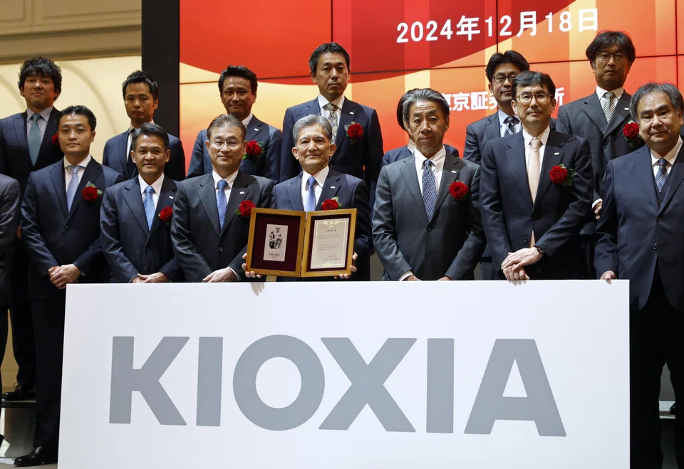 Nobuo Hayasaka (centre), President and CEO of Kioxia Holdings Corporation, poses holding a certificate during a ceremony marking the Japanese flash memory maker debut on the Tokyo Stock Exchange, Dec 18. 