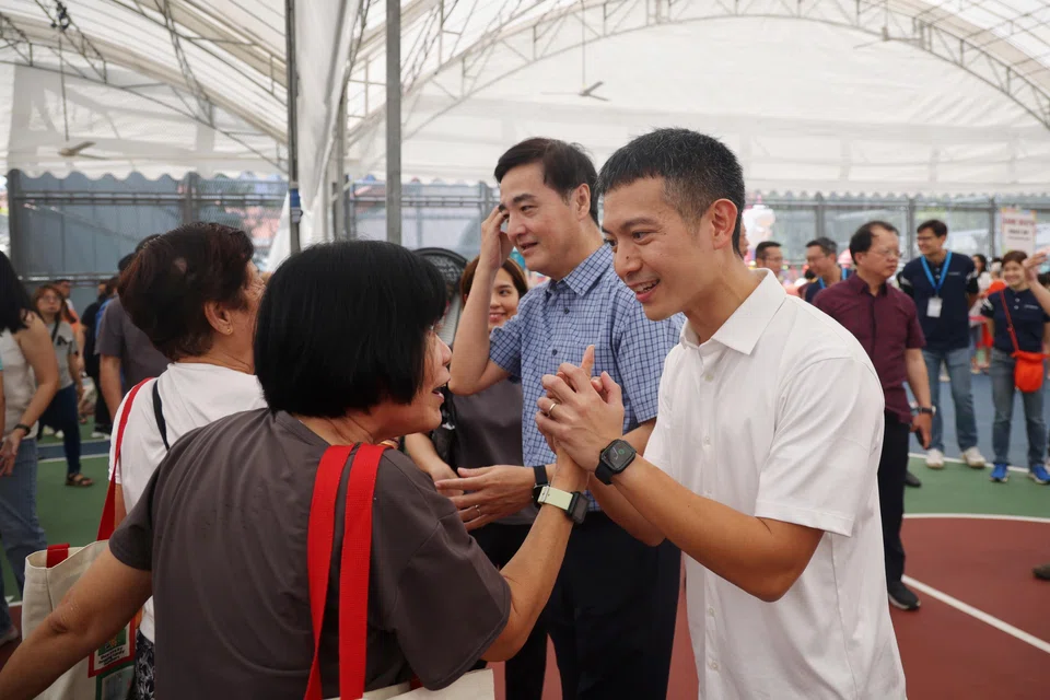 Shawn Loh (in white) and Senior Minister of State Heng Chee How (in blue) greeting residents in Jalan Besar GRC at an event on Sunday together with the constituency's current MPs.