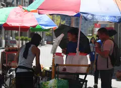 People buying coconut water to cool themselves along a road in Manila on Apr 24, as extreme heat affected the country.