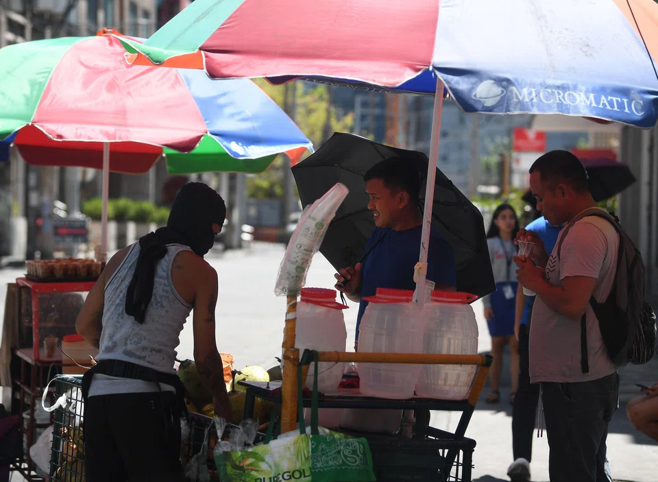 People buying coconut water to cool themselves along a road in Manila on Apr 24, as extreme heat affected the country.