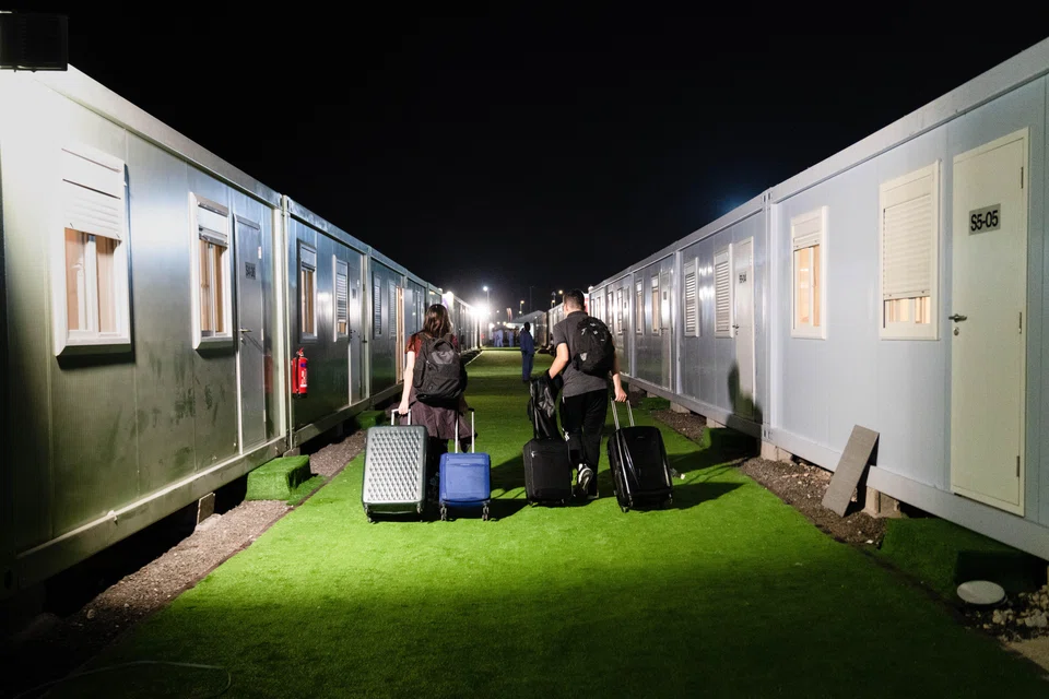 Gihana Fava and Renan Almeida, soccer fans from Brazil, head for their rented room after checking in at Fan Village at the World Cup in Doha, Qatar, on Nov. 22, 2022. Fan Village is a sea of shipping containers converted to sleeping quarters, stretching almost as far as the eye can see. (Erin Schaff/The New York Times)