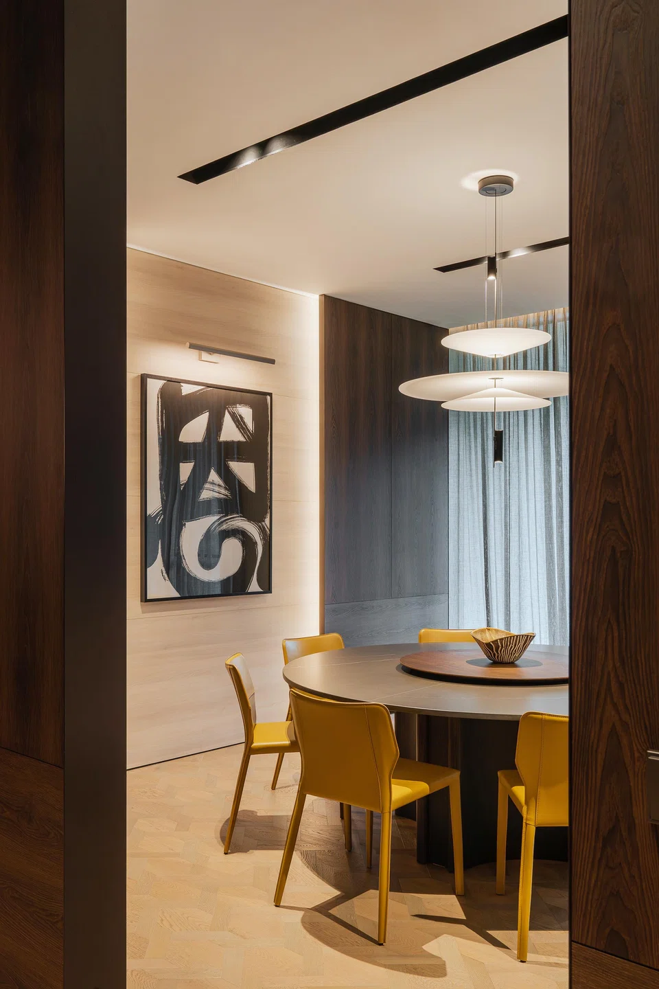 Dark wood frames a calligraphic work in the son’s dining room, tying the textures of the house together.