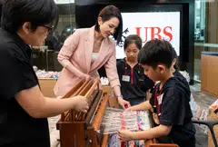 Young Jin Yee (in pink), co-head of UBS global wealth management Asia-Pacific and country head at UBS Singapore, with Care Corner students as they weave a 60-metre-long tapestry as part of the Art for All programme.