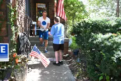 Jason Brown gives a neighbour a handcrafted political sign featuring a simple blue dot, at his home in Omaha, Nebraska, Sept 30, 2024. 