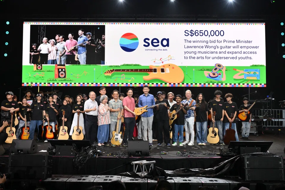 PM Lawrence Wong (in red) and Forrest Li (in blue), chairman and group CEO of Sea, with youth from the Gift-A-Guitar programme.
