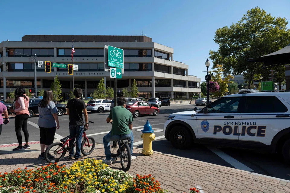 People watch as Springfield Police Department officers investigate the Springfield City Hall after bomb threats were made against buildings earlier in the day in Springfield, Ohio, Sept 12, 2024. 