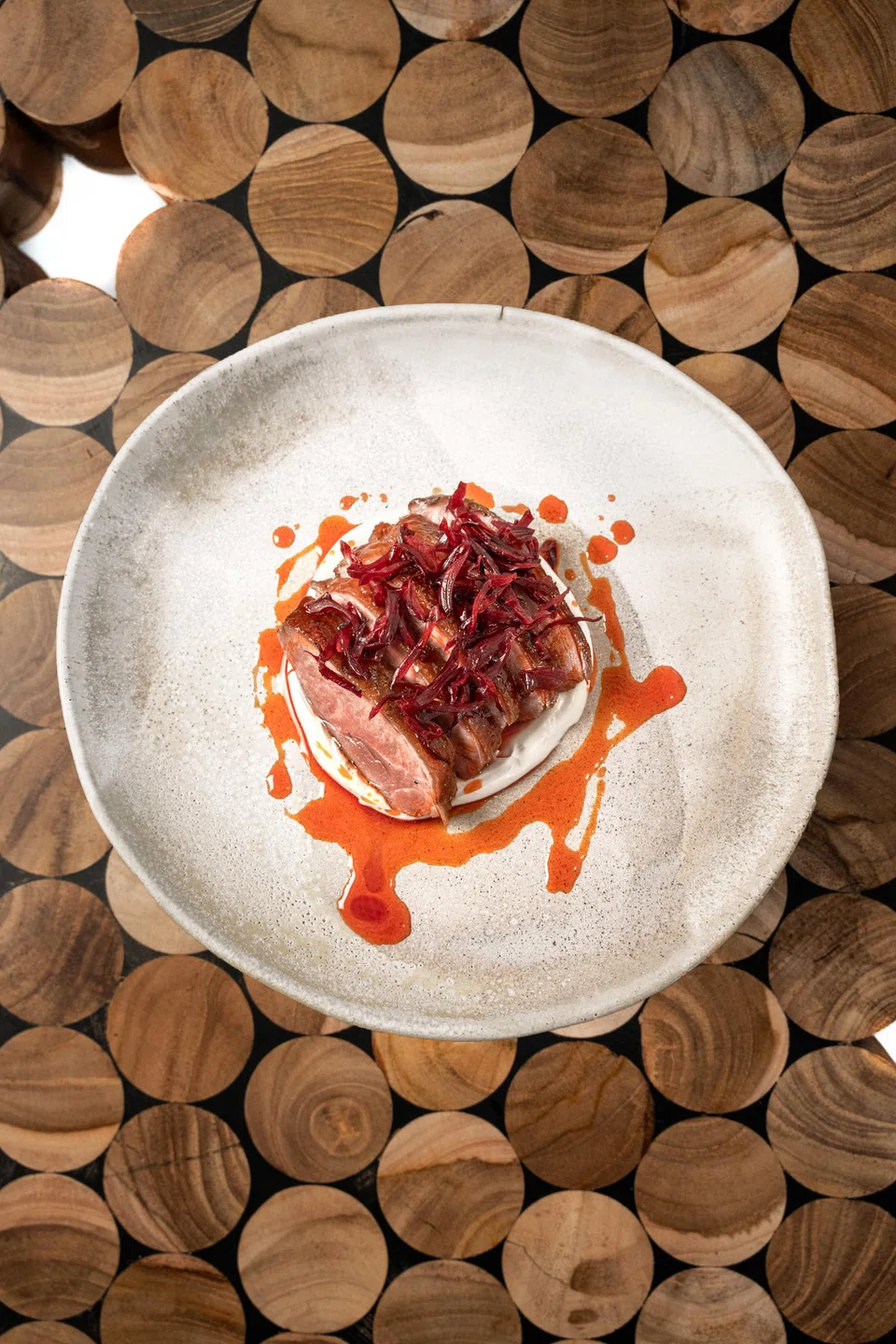 Grilled duck is garnished with a roselle garnish.