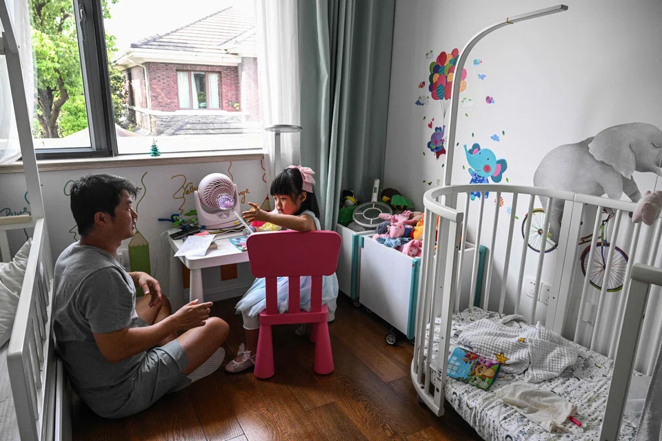Stay-at-home dad Chen Hualiang plays with his daughter at their home in Shanghai, China, Aug 9, 2024. 