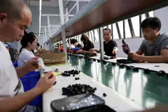 Employees work at an assembly line producing car smartphone holders at a plastics factory, Dongguan, China, April 2, 2026.  