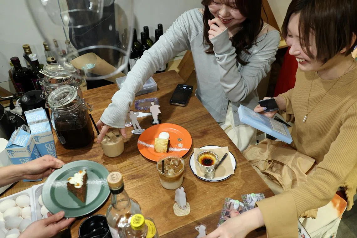 Momoka Matsui and her co-worker Saki Matsumoto prepare to take photos of acrylic stand figure models of their favourite idols with cakes and teas, which they ordered at After All Coffee, where Matsui’s favourite boy band stopped by, Tokyo, Japan, March 23, 2025.
