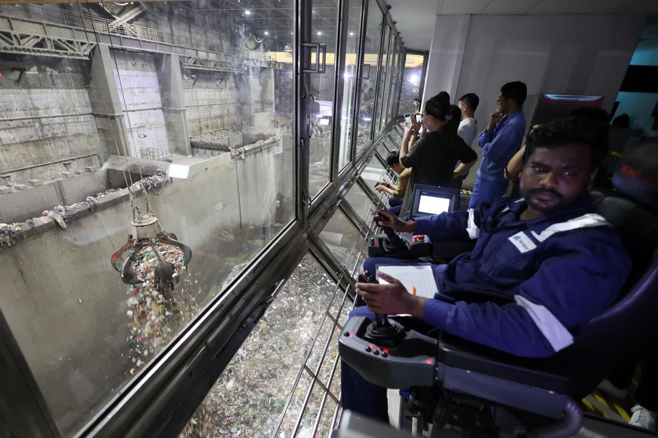  A worker controlling a claw to pick up waste at NEA’s TuasOne waste-to-energy plant; removing residual emissions is one of the strategies the government is studying in a bid to achieve its national target of achieving net-zero emissions by 2050.