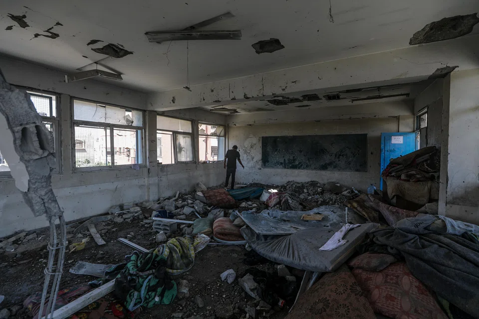  Palestinians inspect the damage at a destroyed UNRWA school building following an Israeli airstrike in Al Nusairat refugee camp in the central Gaza Strip.