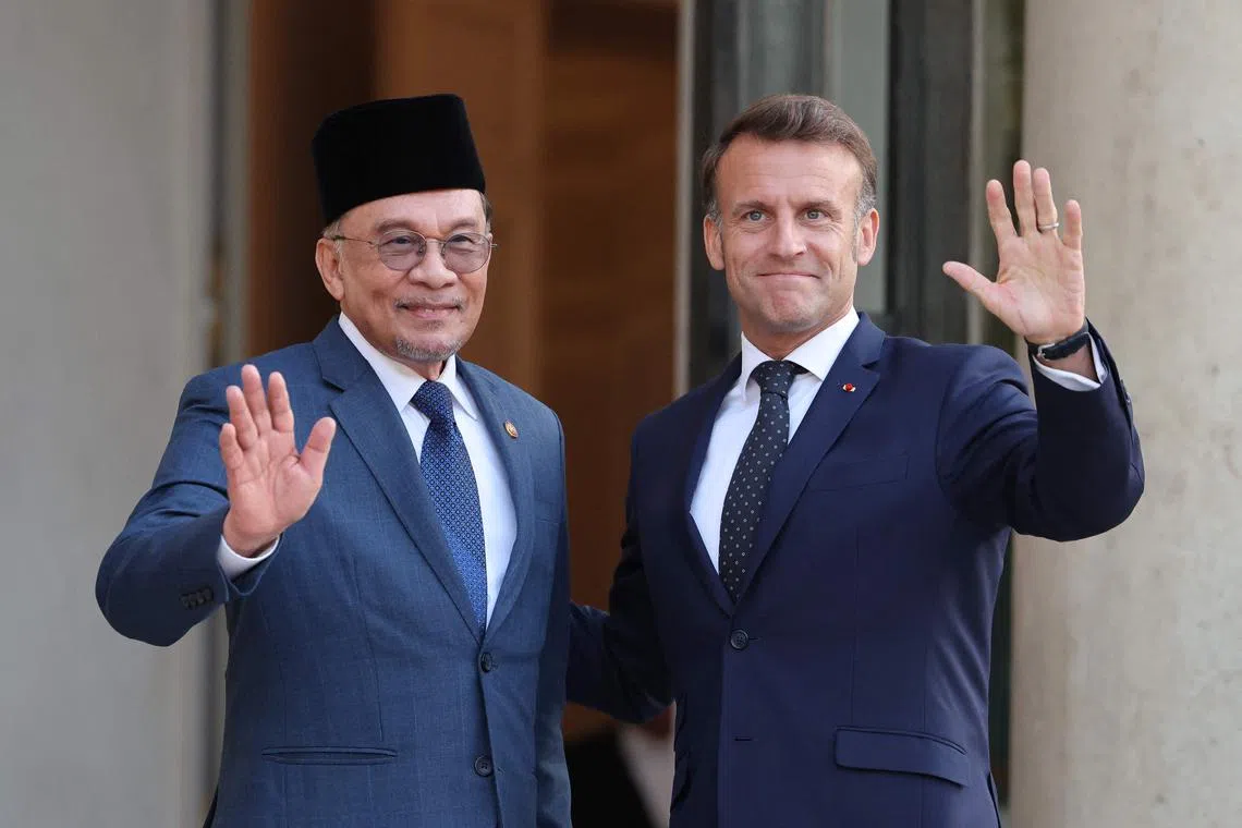 France's President Emmanuel Macron (right) and Malaysia's Prime Minister Anwar Ibrahim wave prior to a working dinner at the Elysee Palace in Paris on Jul 4.