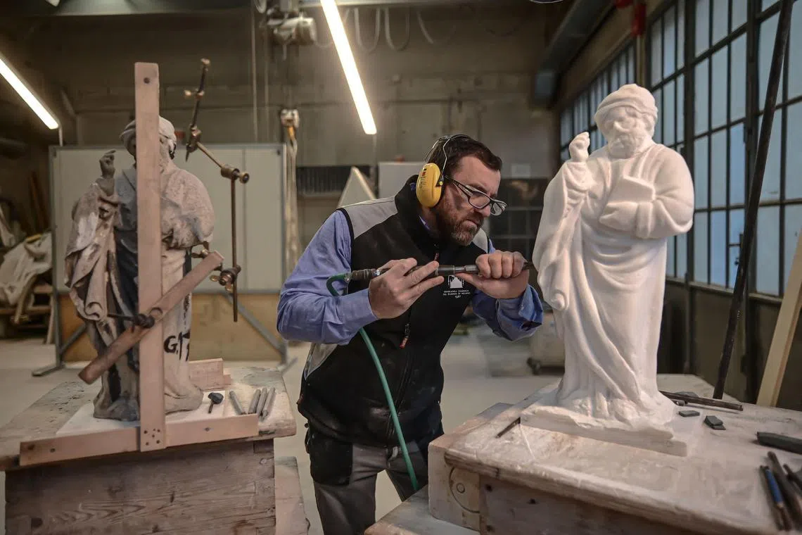 Sculptor Giovanni Calderino, 46, carves a Candoglia marble statue with a pneumatic hammer, as part of a project to replace ageing and damaged statues on Milan's gothic cathedral with perfect replicas.