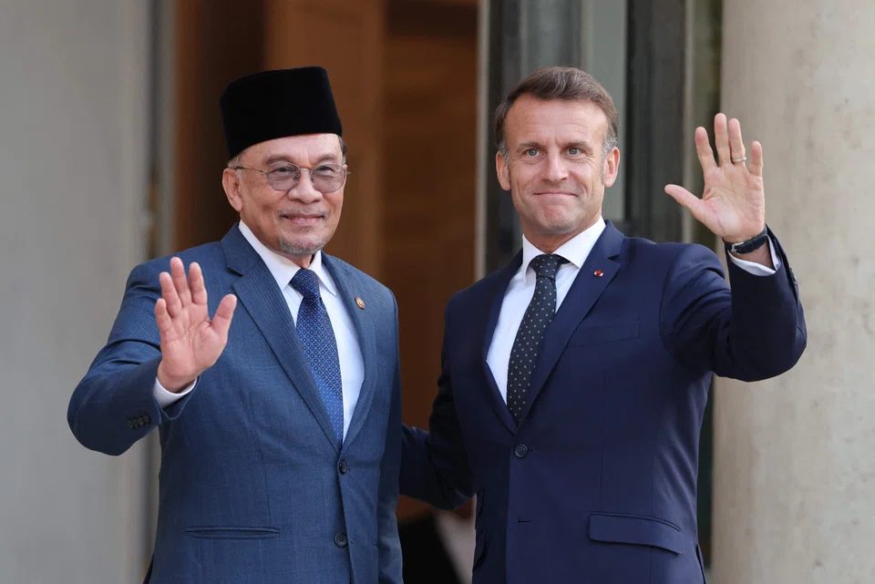 France's President Emmanuel Macron (right) and Malaysia's Prime Minister Anwar Ibrahim wave prior to a working dinner at the Elysee Palace in Paris on Jul 4.
