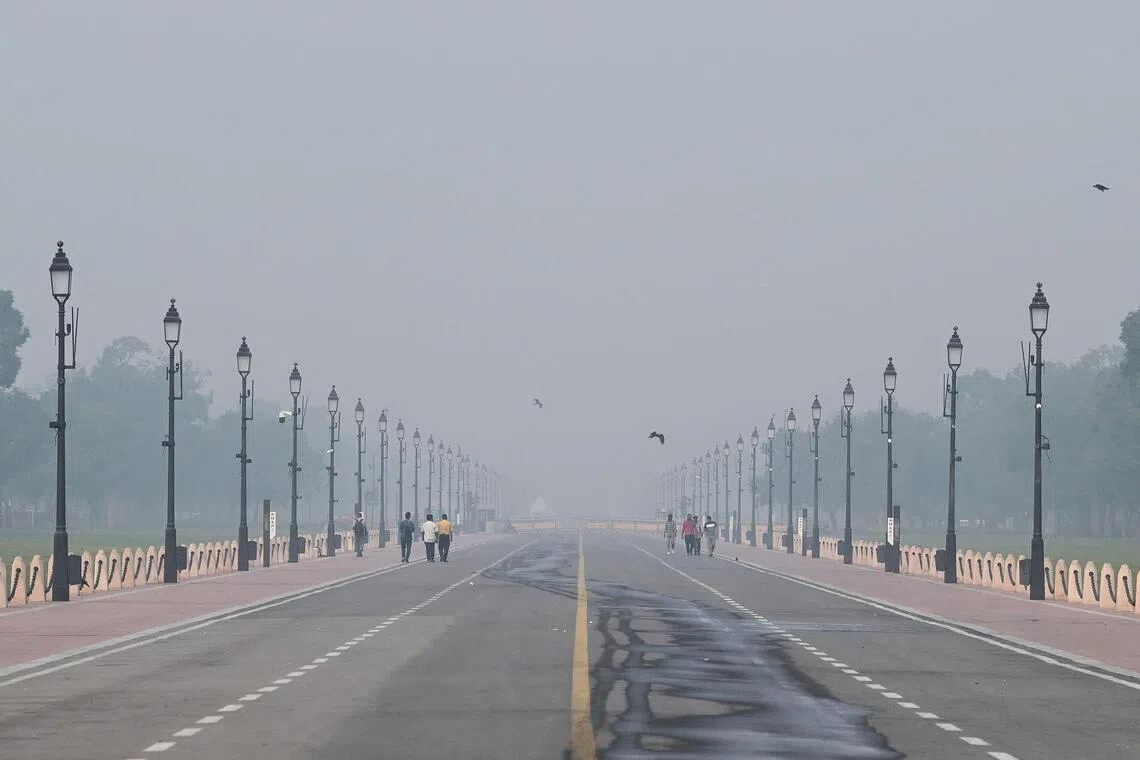 Pedestrians walk along the Kartavya Path near India Gate as thick smog engulfs the city skyline in New Delhi, India, Oct 22, 2025. 