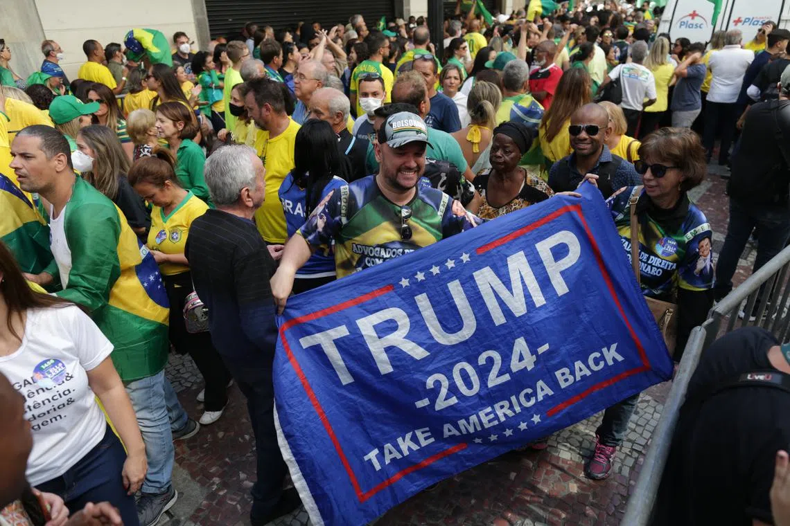 A man holds a flag of support for Donald Trump during the first re-election campaign event of Brazil's far-right president Jair Bolsonaro in Juiz de Fora, Brazil, on Aug 16. 