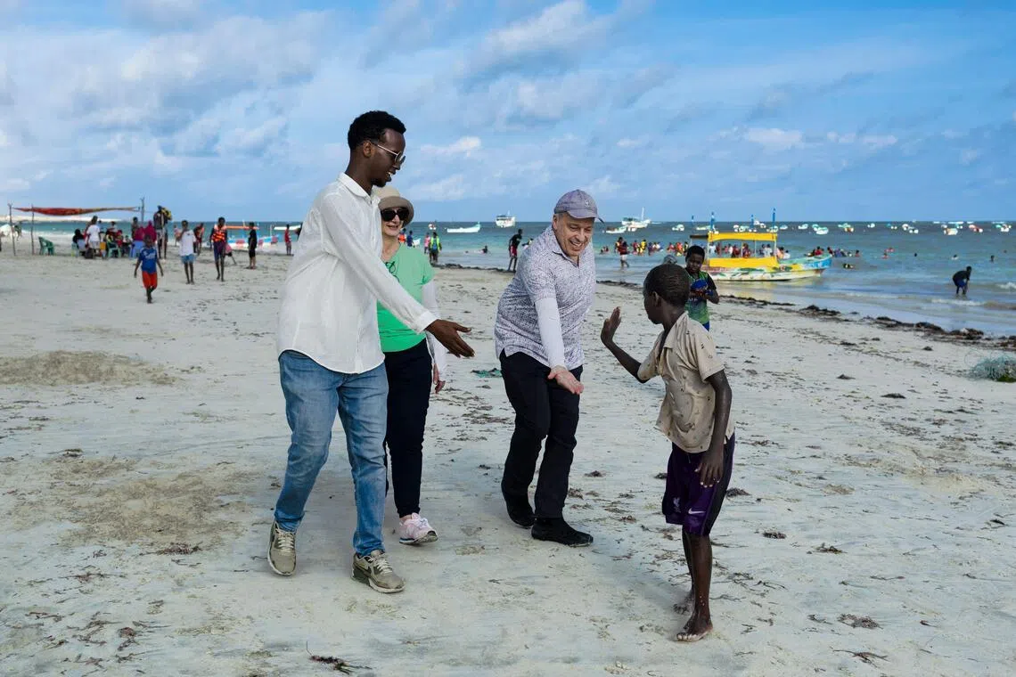 US tourists Richard and Sheryl with their local guide, interacting with local youth on their walk on Lido beach during a guided tour in Mogadishu. 