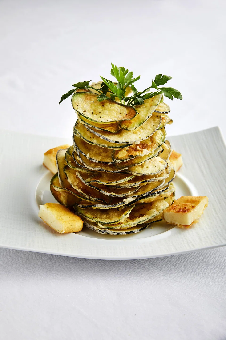The Milos Special is a tower of lightly fried paper thin zucchini and eggplant, paired with tzatziki and Kefalograviera saganaki cheese.