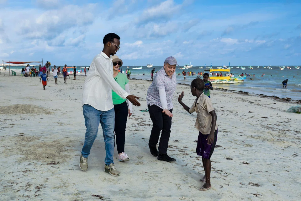 US tourists Richard and Sheryl with their local guide, interacting with local youth on their walk on Lido beach during a guided tour in Mogadishu. 