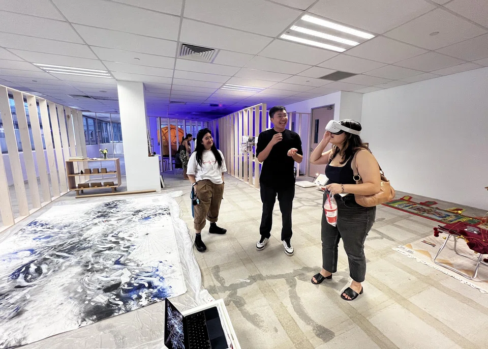 At Nothing But A Day Dream, Benedict Yu (centre) explains his art executed as a large painting (left) and a virtual reality experience. 