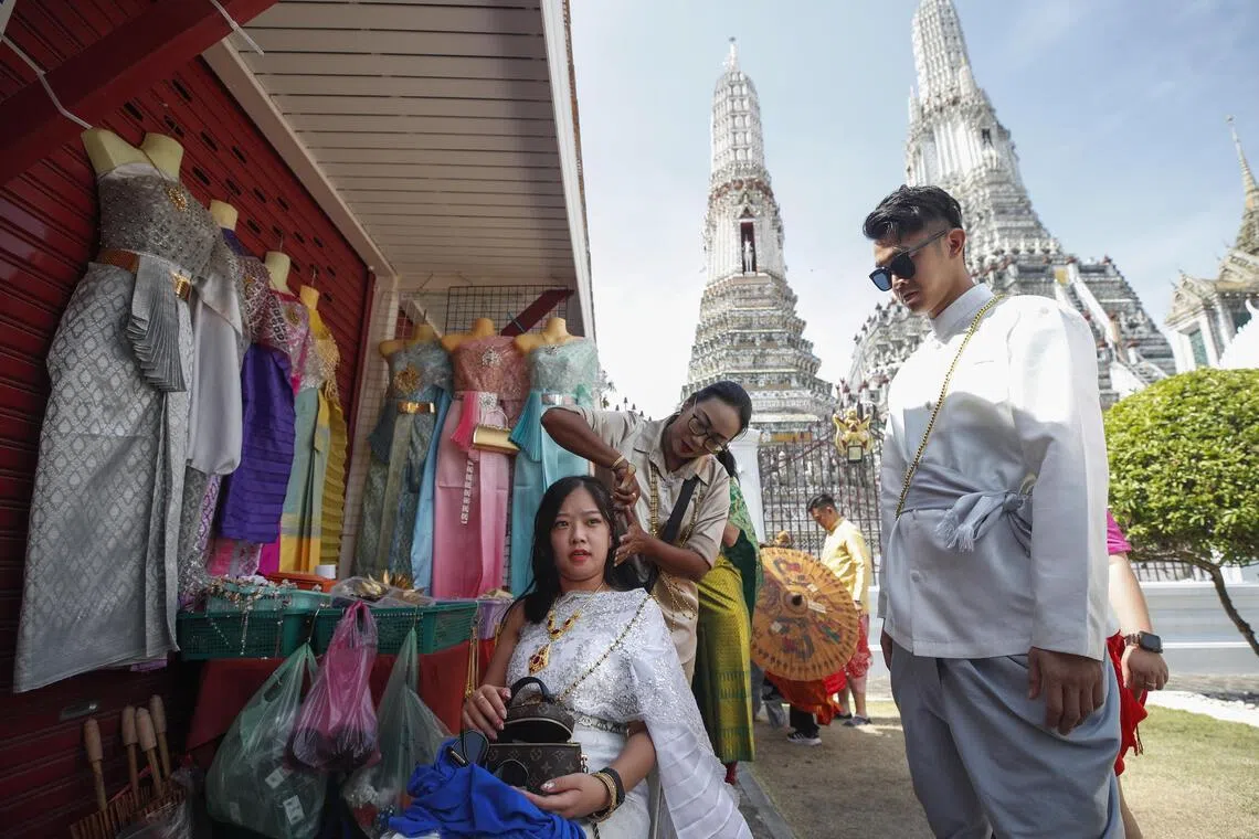 epa10424388 A Thai clothing rental vendor assists Chinese tourists dressing in Thai traditional costumes, during a visit to Wat Arun or Temple of Dawn in Bangkok, Thailand, 23 January 2023. Thailand's tourism and business related activities are in recovery stimulated by the influx of Chinese tourists after China lifted COVID-19 travel restrictions. Thailand is projected to welcome five million Chinese visitors in 2023 with 29,4000 tourists from mainland China expected to arrive during Lunar New Year, according to the Tourism Authority of Thailand.  EPA-EFE/RUNGROJ YONGRIT