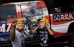Supporters of Republican presidential nominee and former President Donald Trump pose with his masks as they wait in line to attend a campaign rally during a hot and humid day in Harrisburg, Pennsylvania., July 31, 2024.